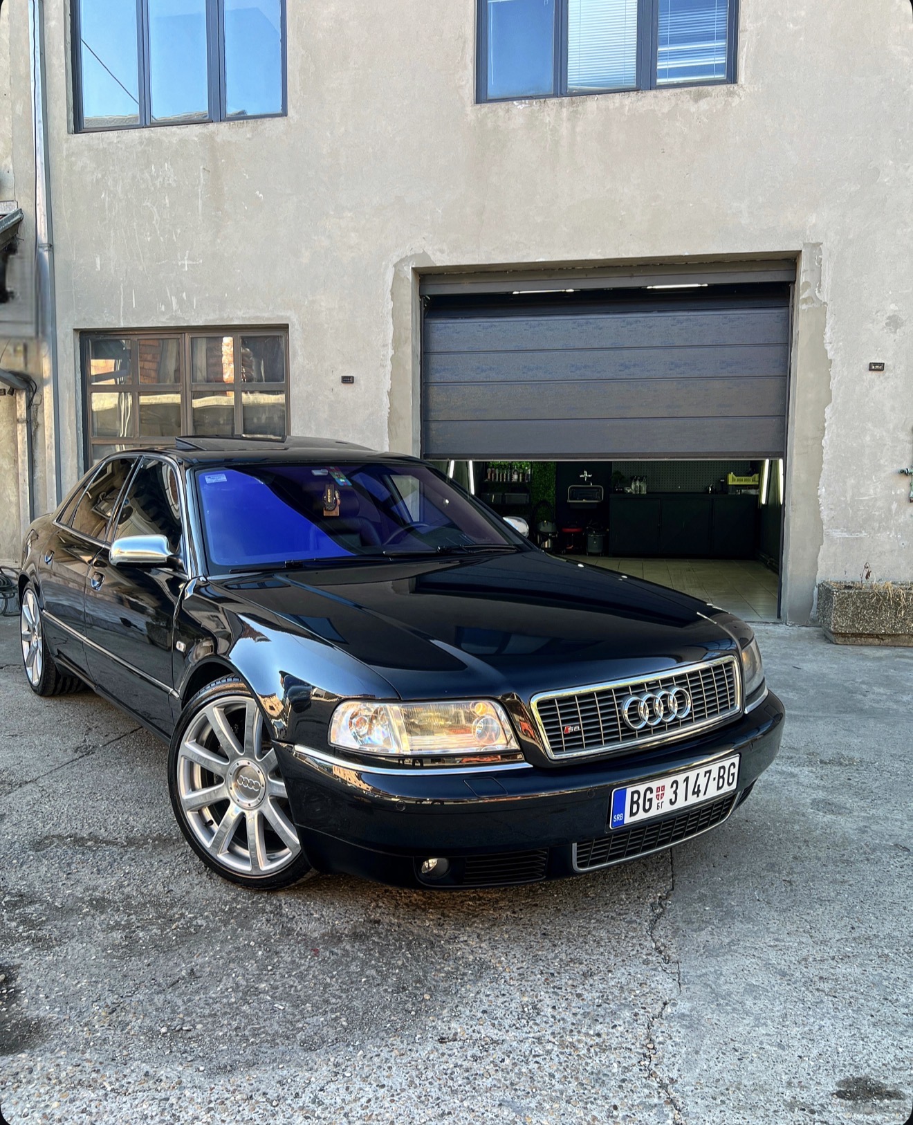 Crna Audi S8 limuzina sa besprekorno poliranim lakom ispred garaže